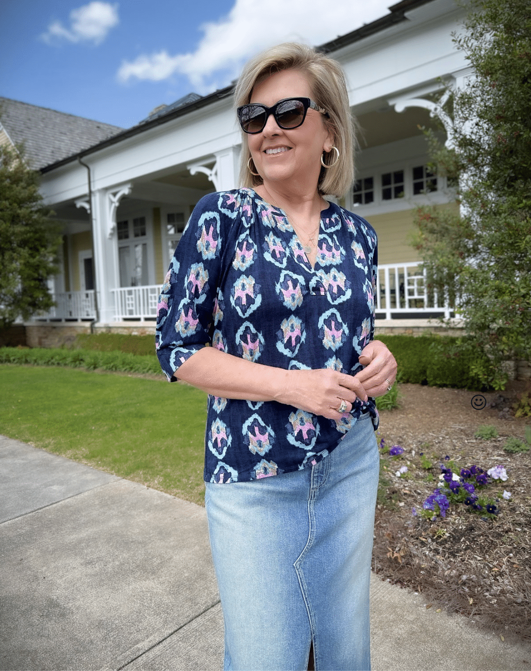 a woman in a blue shirt and denim skirt standing in front of Spring flowers